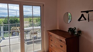 Habitació amb un gran finestral corredís que dona a un balcó, un taulell de fusta i un mirall fixat a la paret.