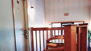 Een hotelkamer met een houten stoel, een tafeltje en een deur met het nummer 12.