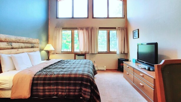 A bedroom with a bed, a television, a dresser, and a ceiling fan.