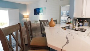 Une cuisine avec un plan de travail en marbre, des chaises en bois et un vase.