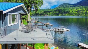 Een vakantiehuis aan het meer met terras, zitplaatsen buiten en een steiger.