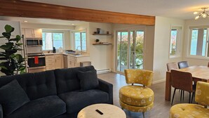 Een moderne keuken met inbouwapparatuur, een eetgedeelte met gele bloemenstoelen, en een grote schuifdeur die leidt naar een balkon.