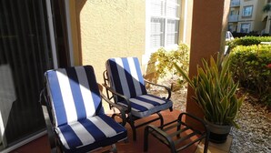 Deux fauteuils de jardin à rayures, placés sur une terrasse, avec une plante en pot à proximité.