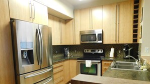 Une cuisine moderne équipée d’appareils électroménagers en acier inoxydable, de meubles de rangement en bois, d’un four à micro-ondes, d’une cuisinière et d’un évier.