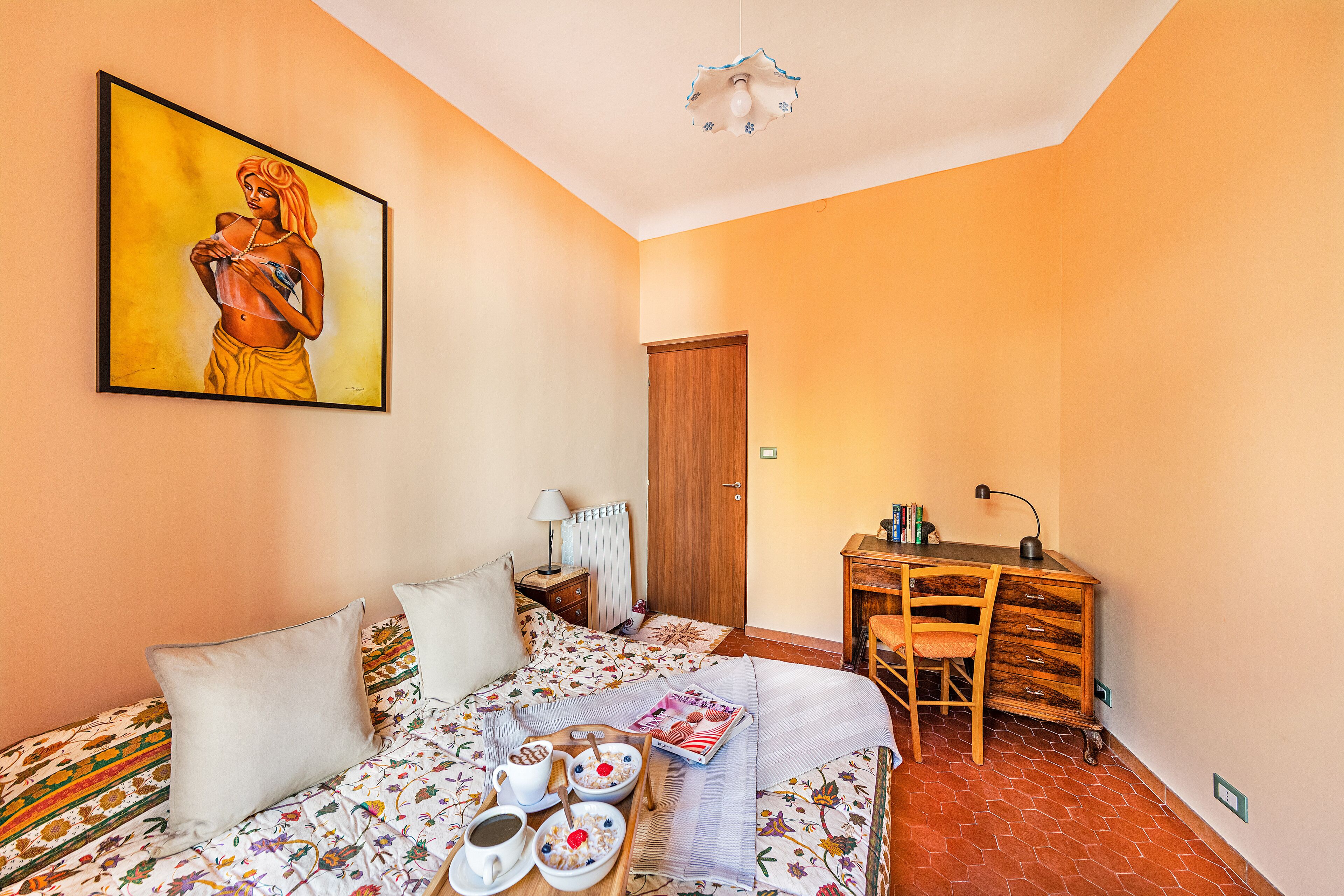 Een slaapkamer met een bed, een bureau en een schilderij aan de muur.