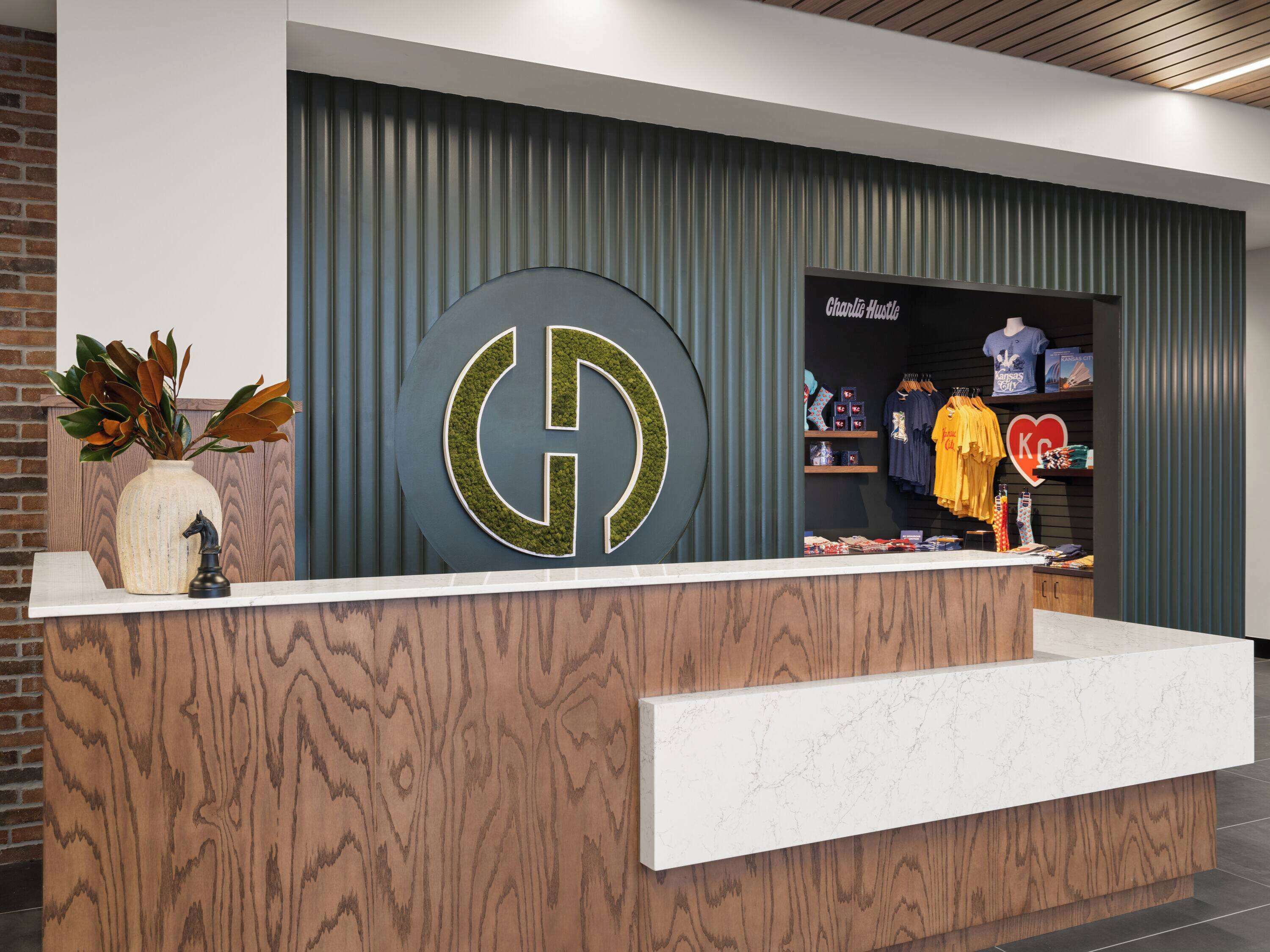 A reception desk with a large logo, a plant, and a display of clothing.