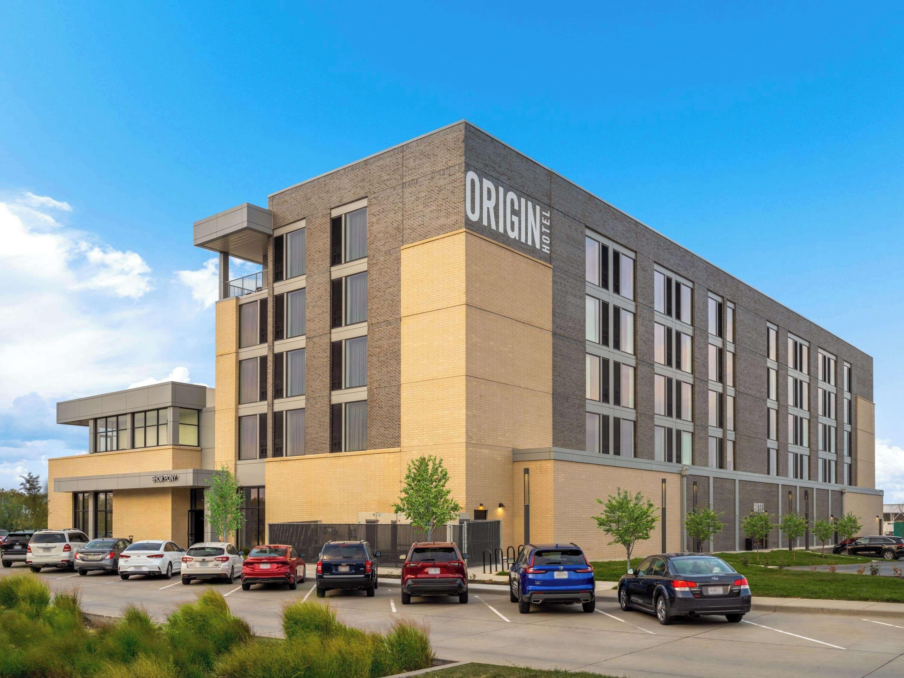 Un moderno edificio de hotel con un letrero destacado que dice "ORIGIN HOTEL".