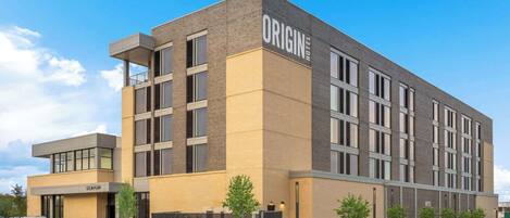 Un moderno edificio de hotel con un letrero destacado que dice "ORIGIN HOTEL".