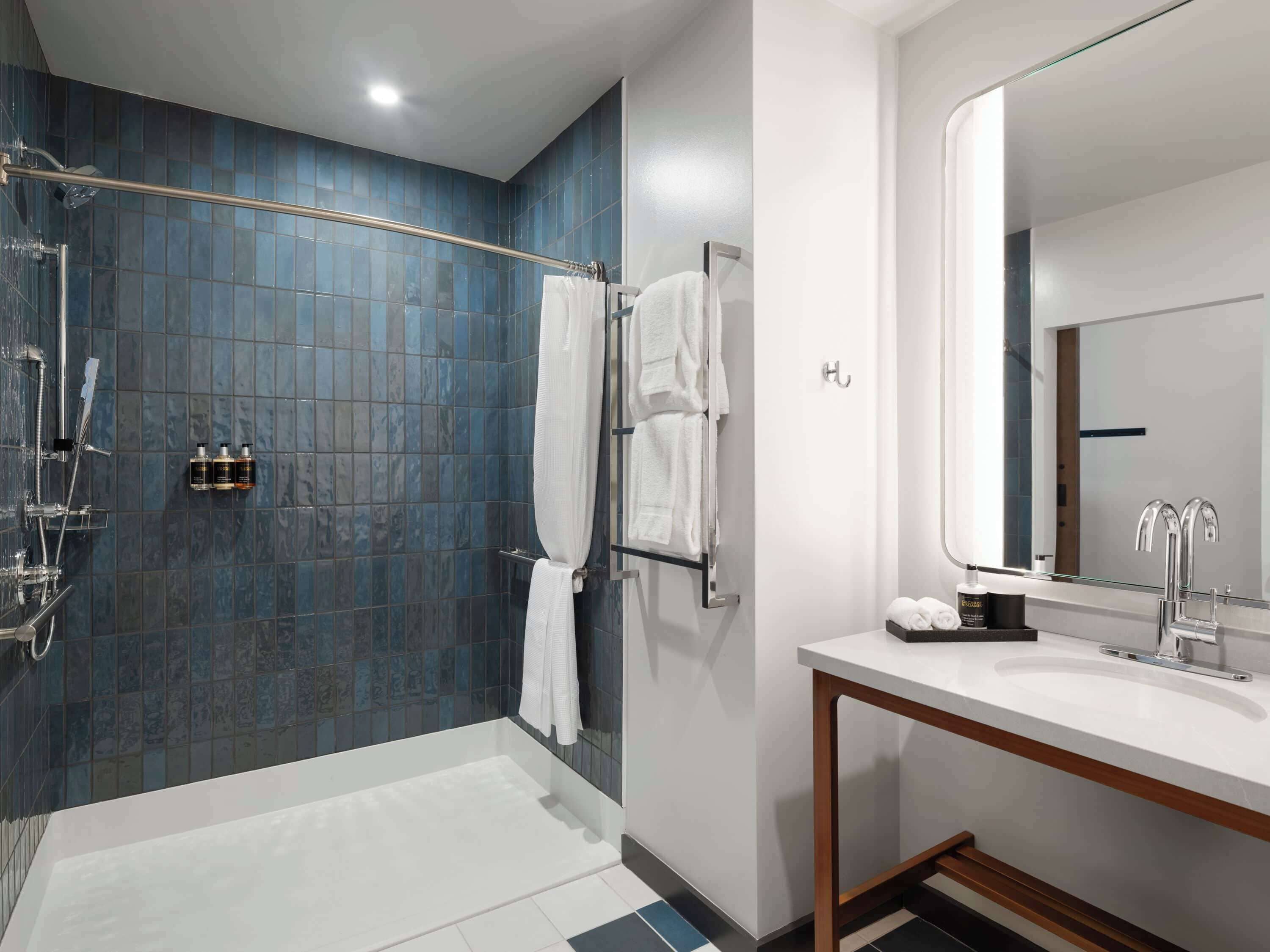 Un bagno moderno con zona doccia, lavandino e specchio.