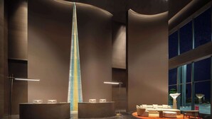 A modern hotel lobby with a tall, illuminated tower, a reception desk, and a seating area with a round table and chairs. - Howard Johnson Royal Hotel Shenzhen (Shenzhen)