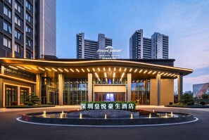 Un hôtel moderne, doté d’une enseigne bien visible, d’une entrée bien éclairée et d’un espace paysager agrémenté d’une fontaine.
