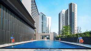A swimming pool with a modern building and high-rise apartments in the background. - Howard Johnson Royal Hotel Shenzhen (Shenzhen)