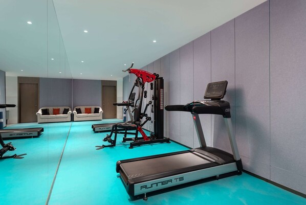 Un gimnasio moderno con cinta de correr, elíptica y máquinas de pesas.