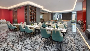 A modern dining area with marble flooring, teal chairs, and a central bar area. - Wingate by Wyndham Urumqi Railway Station (Ürümqi)