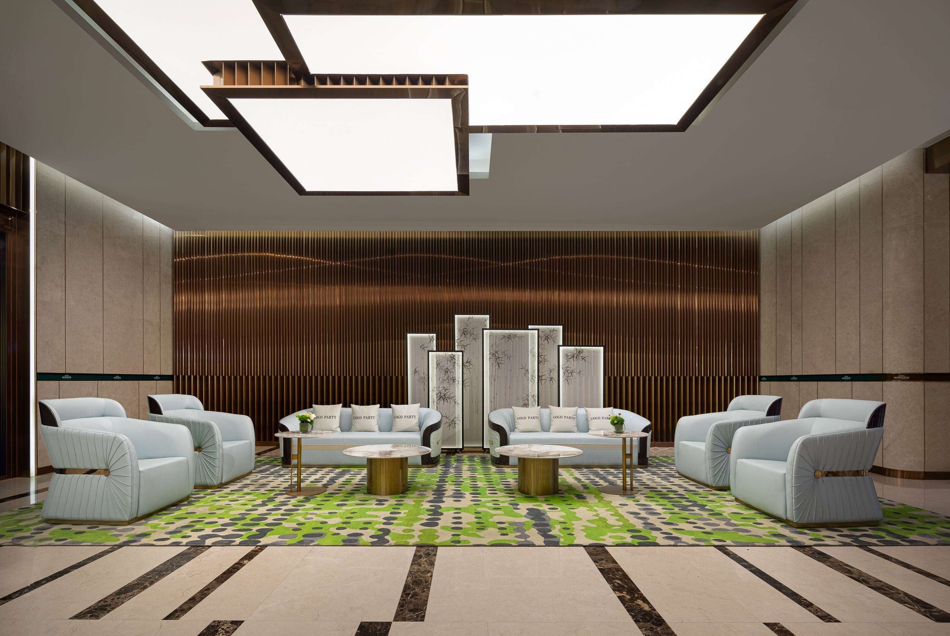 A modern lobby with seating, a patterned carpet, and a skylight.