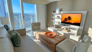 A modern living room with a large TV, a wooden coffee table, and a sofa. - Divine 2 Bedroom Apt at Lyfe Resort (Hollywood Beach)
