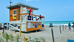 A lifeguard tower with a sign indicating 'Lifeguard on Duty' and a flag. - Divine 2 Bedroom Apt at Lyfe Resort (Hollywood Beach)