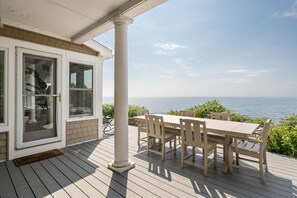 A covered outdoor seating area with a table and chairs, overlooking a body of water. - Spacious York Home with Ocean Views & Hot Tub (York)