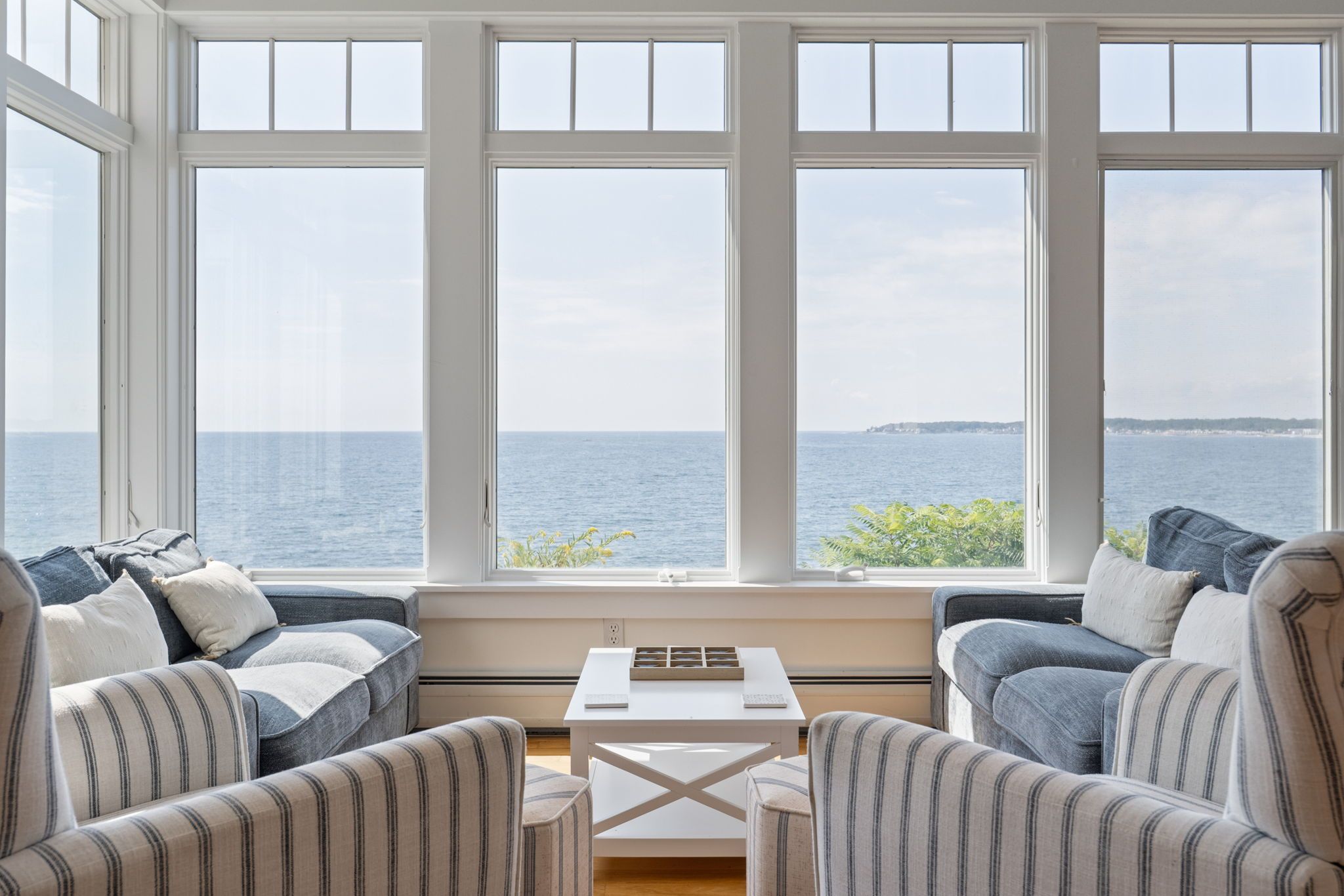 Una habitación con un amplio ventanal con vistas al mar, que incluye un sofá y una pequeña mesa.