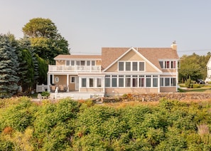 A two-story house with a balcony, a stone wall, and a garden with ferns. - Spacious York Home with Ocean Views & Hot Tub (York)