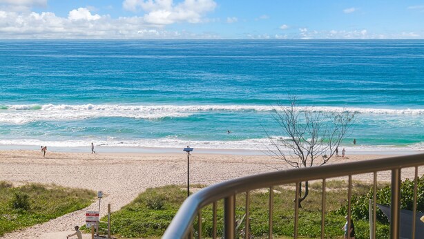 A beach with a clear view of the ocean, a sandy shore, and a few people.