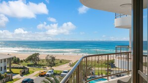 A balcony with a view of the beach and ocean.