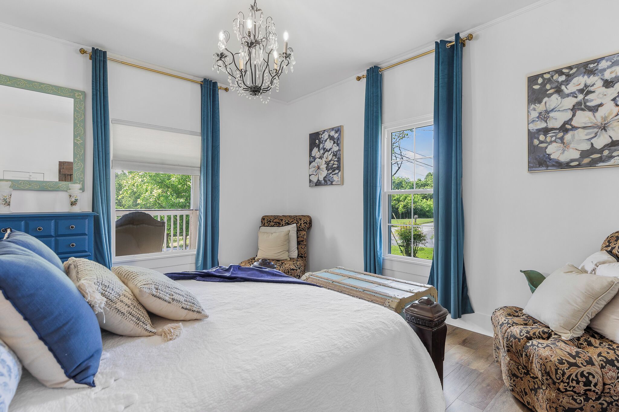 A bedroom with a large bed, a dresser, a chair, and a window with curtains.
