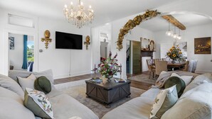 Un salón amplio con un gran sofá, una mesa de centro de madera oscura y una araña.