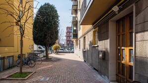 A narrow brick-paved alleyway with a tree, bicycles, and a building with a wooden door and window. - San Donato Cozy Apartment by Wonderful Italy (Bologna)