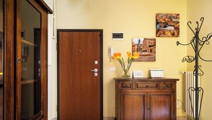 A wooden door, a cabinet with a vase of flowers, and a coat rack. - San Donato Cozy Apartment by Wonderful Italy (Bologna)