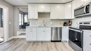 Una cucina moderna con mobili bianchi, elettrodomestici in acciaio inossidabile e un'isola centrale.