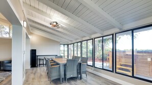 Un'ampia stanza con un grande tavolo da pranzo e sedie, ampie finestre che offrono vista sull'esterno e un soffitto con travi a vista.