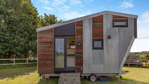 A small, single-story cabin with a modern design, featuring a large sliding door and a small porch area. - Fox Tiny House- UK47395 (Foxley, near Dereham)