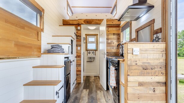 A compact kitchen with wooden cabinetry, a built-in oven, and a stove. - Fox Tiny House- UK47395 (Foxley, near Dereham)