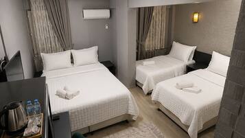 A hotel room with two beds, a desk, a chair, a coffee maker, and a water bottle.