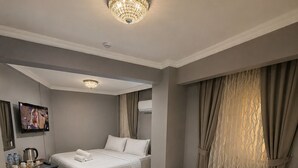 A hotel room with two beds, a desk, a television, and a chandelier. - Aras Hotels Çorlu (Corlu)