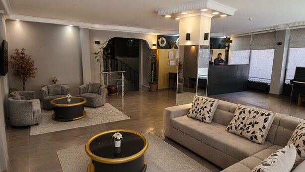 A modern living room with a sofa, armchairs, a coffee table, and a reception desk. - Aras Hotels Çorlu (Corlu)