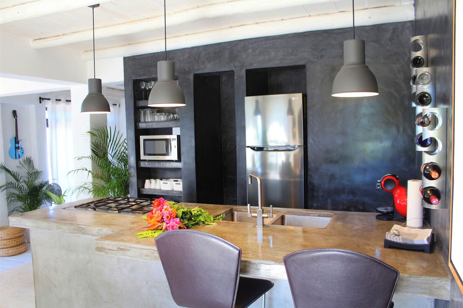 A modern kitchen with a central island, stainless steel appliances, pendant lighting, and a built-in microwave.