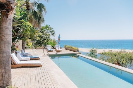 Una piscina al aire libre, sombrillas, sillones reclinables de piscina
