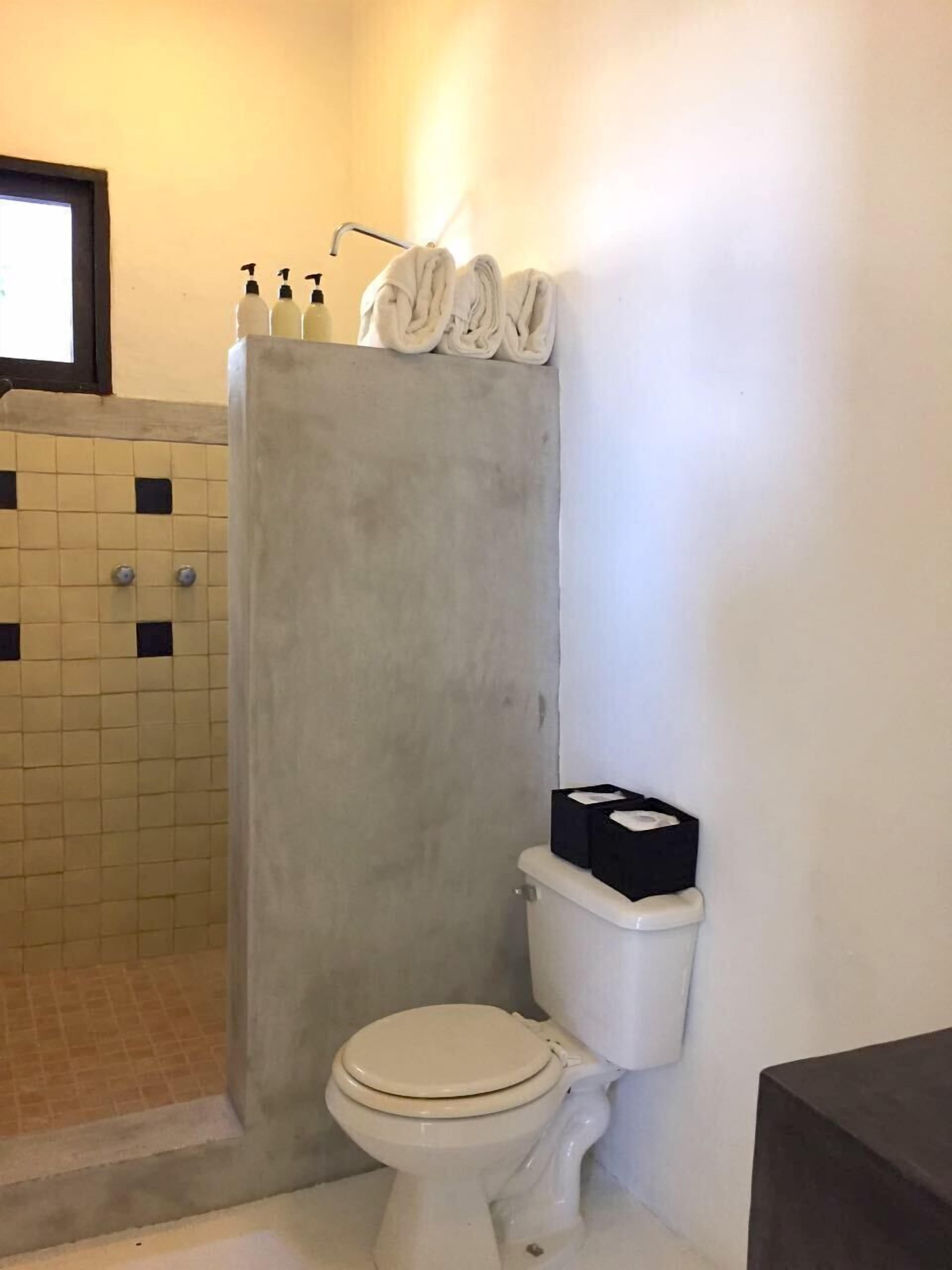 A bathroom with a toilet, a shower curtain, and a tiled wall.