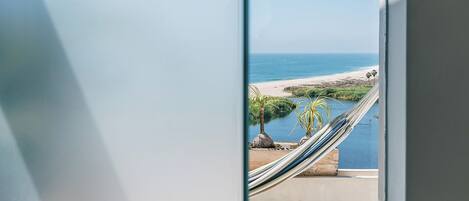 A balcony with a view of the ocean, a hammock, and a small pool.