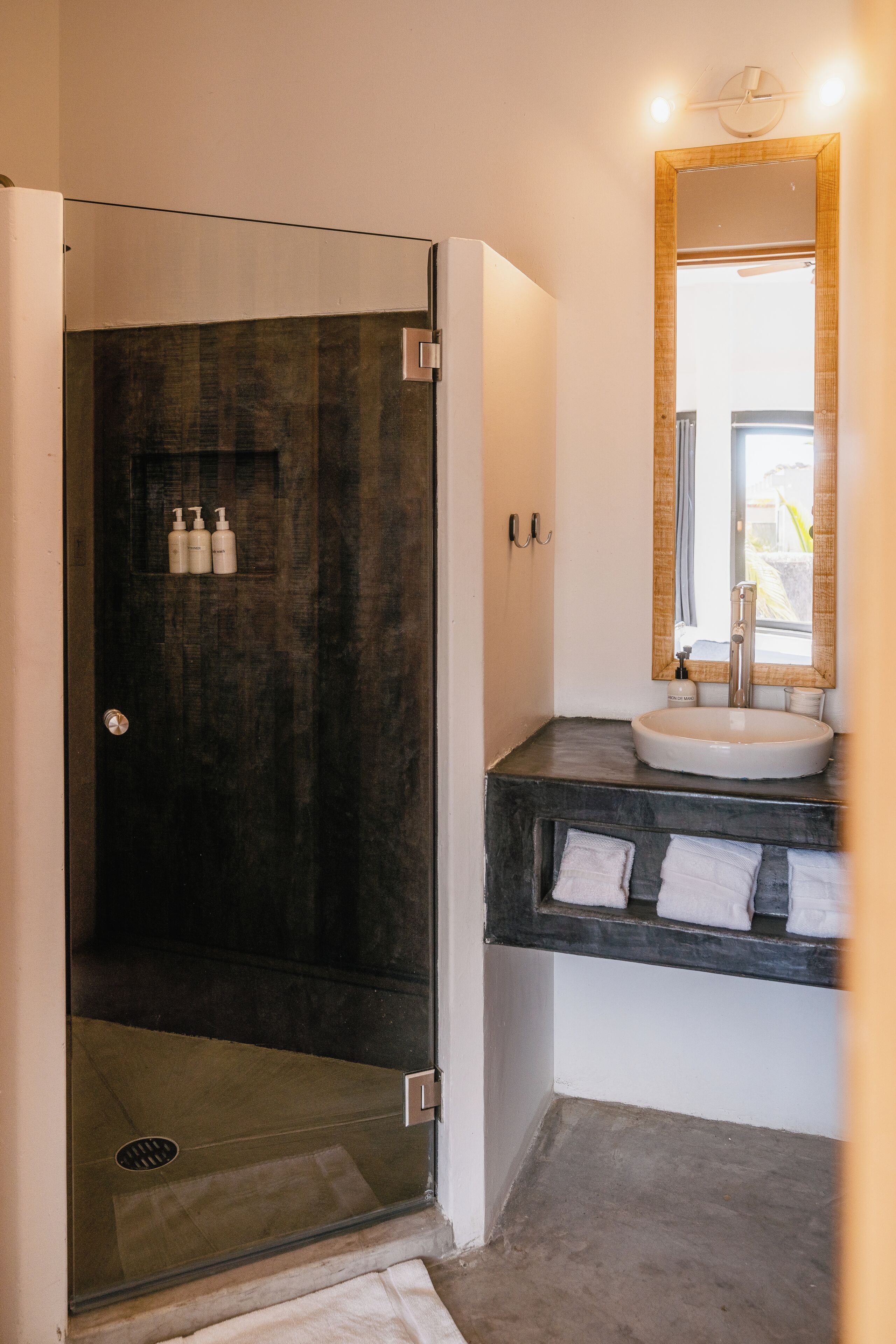 A modern bathroom with a glass-enclosed shower, a sink with a mirror, and a towel rack.