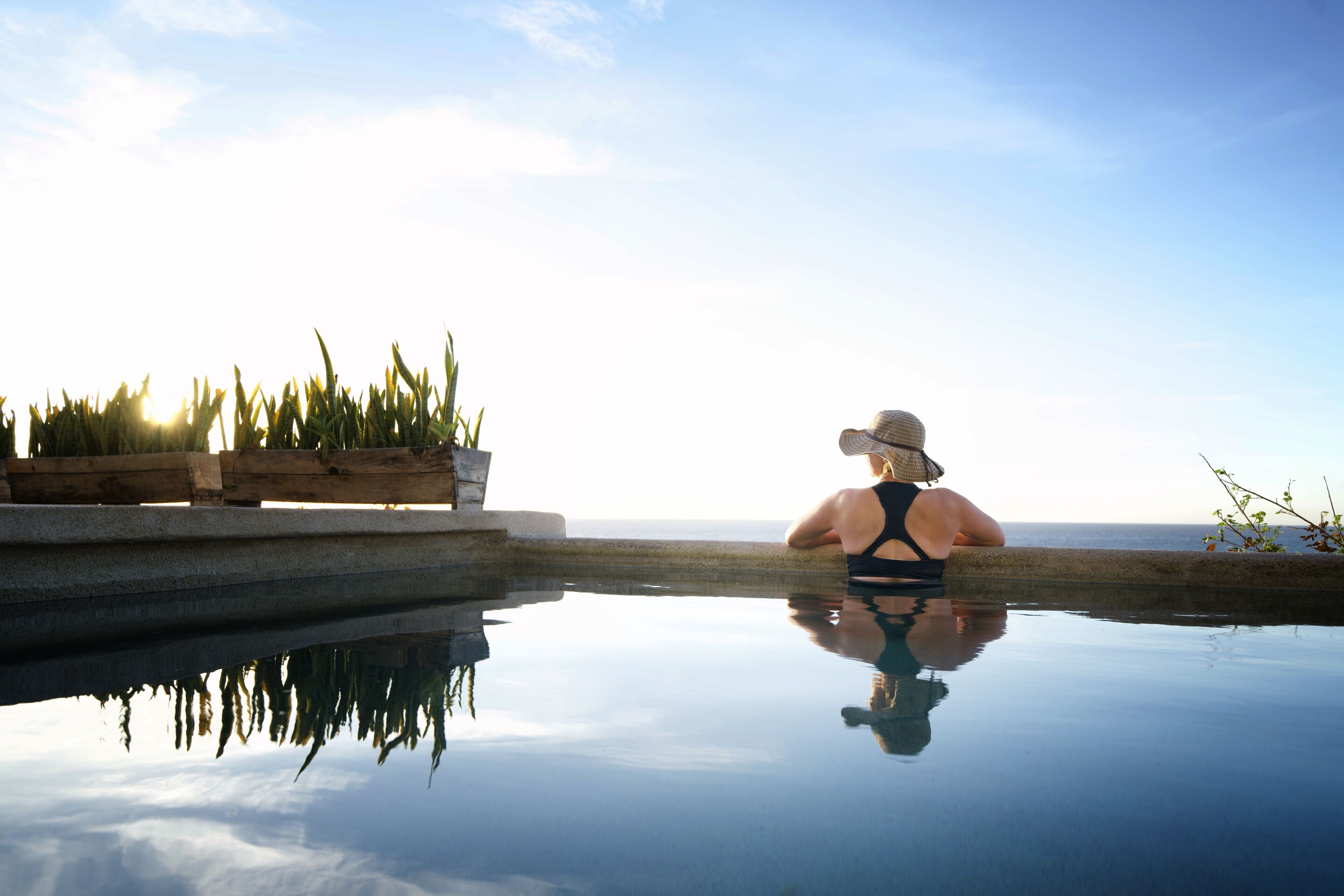 A person relaxing by a reflective pool with a view of the ocean.