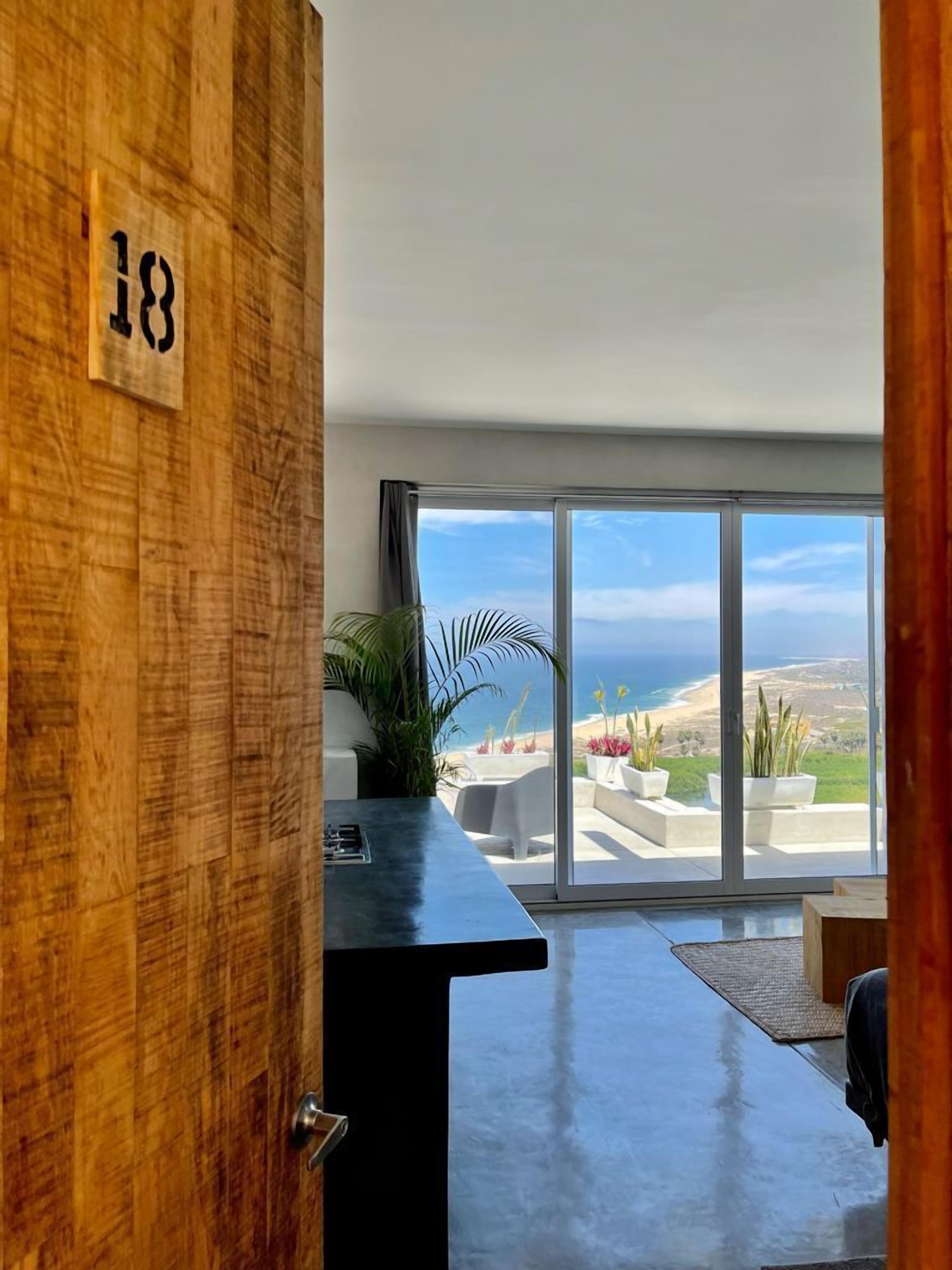 Une pièce dotée d’une grande porte-fenêtre coulissante donnant sur un balcon avec vue sur la côte.