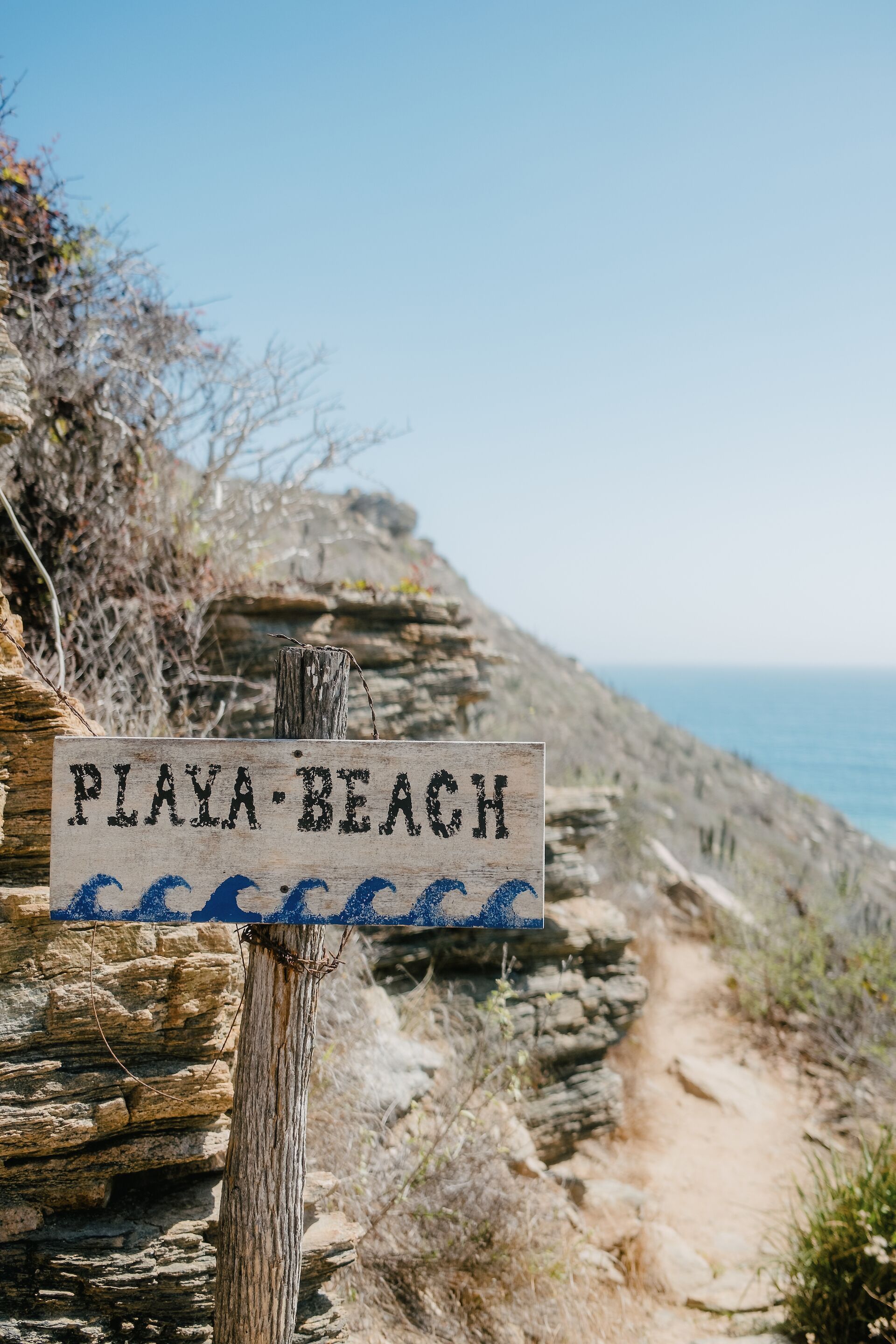 A wooden sign with the text "PIAYA BEACH" and a blue wave symbol.