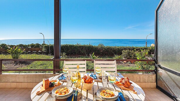 A table set for a meal with a view of the ocean. - La Brise Apartment by Wonderful Italy (Sanremo)