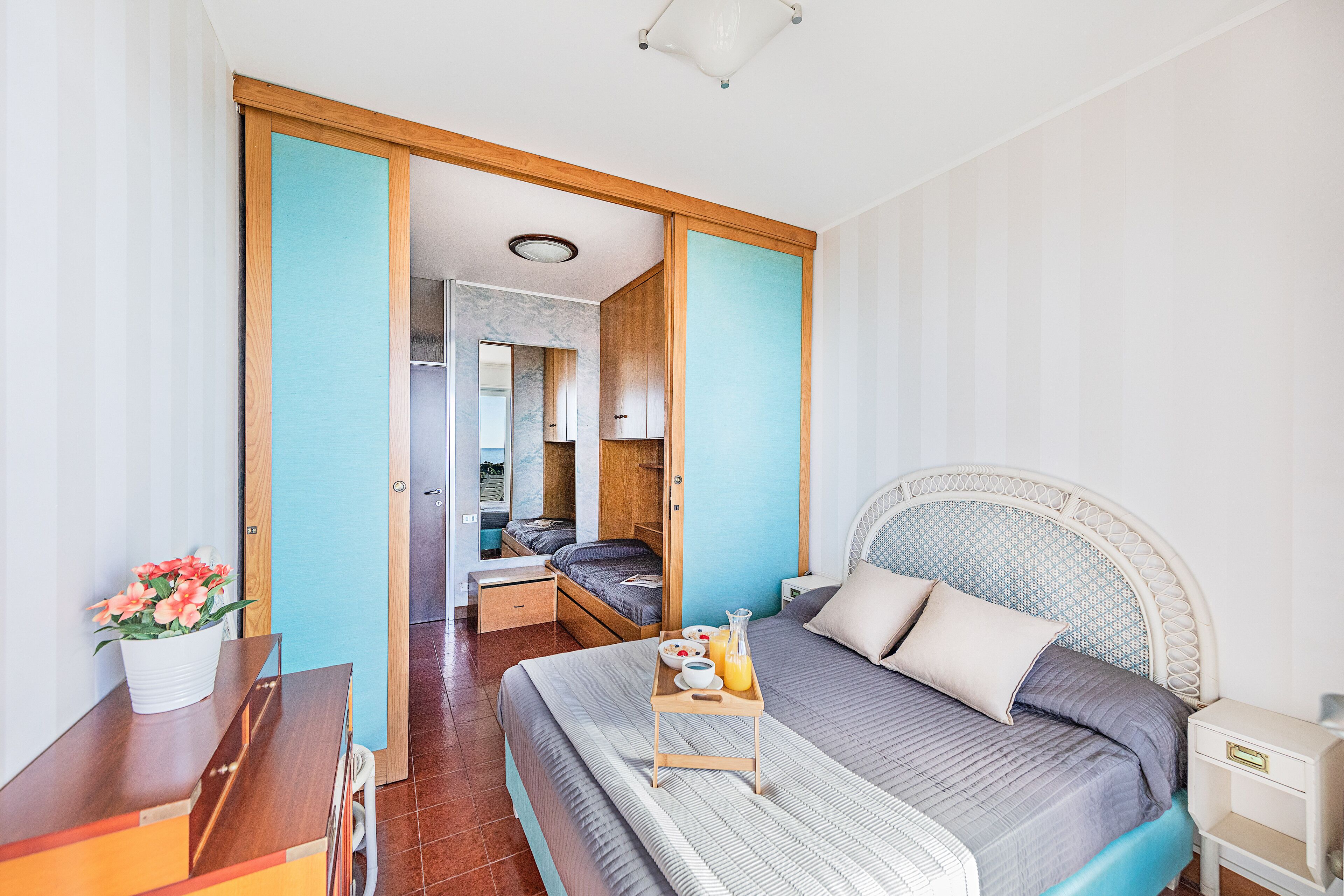 Ein Schlafzimmer mit einem Bett, einem Nachttisch und einem kleinen Tisch mit Frühstücksgebäck.