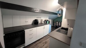 A compact kitchen with white cabinets, a black countertop, a coffee maker, and a sink.