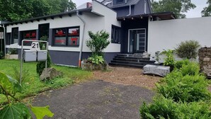 A modern two-story building with a flat roof, a small front garden, and a sign indicating room number 21.