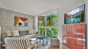 A modern living room with a sofa, coffee table, and TV. - Treetop Retreat Cozy 2 Bedroom in Grove (Miami)